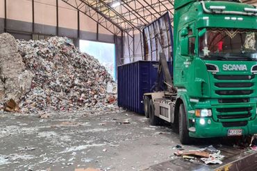 Kuorma-auto nostaa vaihtolavaa jätteenkäsittelylaitoksella